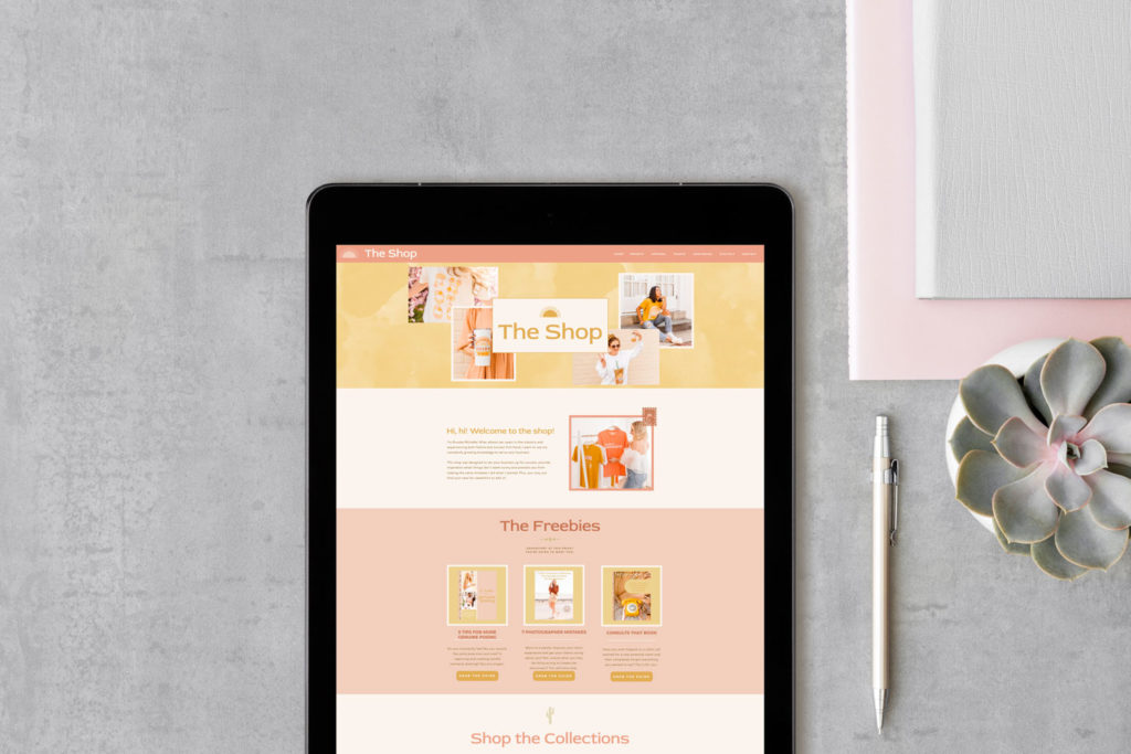 An ipad has a pink and yellow website pulled up next to a pen, a succulent, and a pink and grey journal.