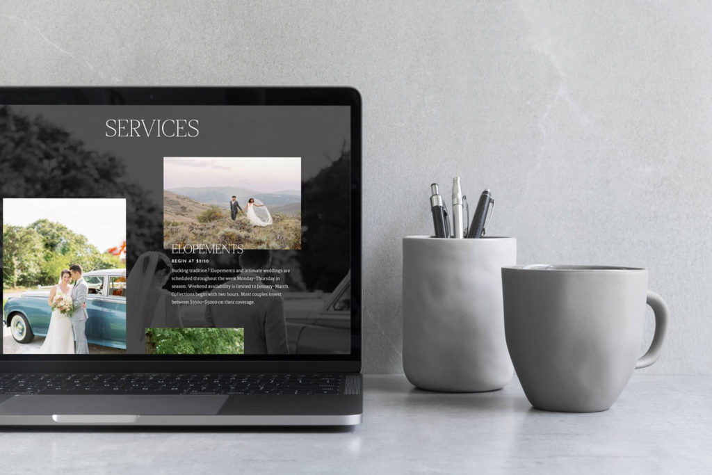 Photographer website pulled up on a laptop next to two gray cups