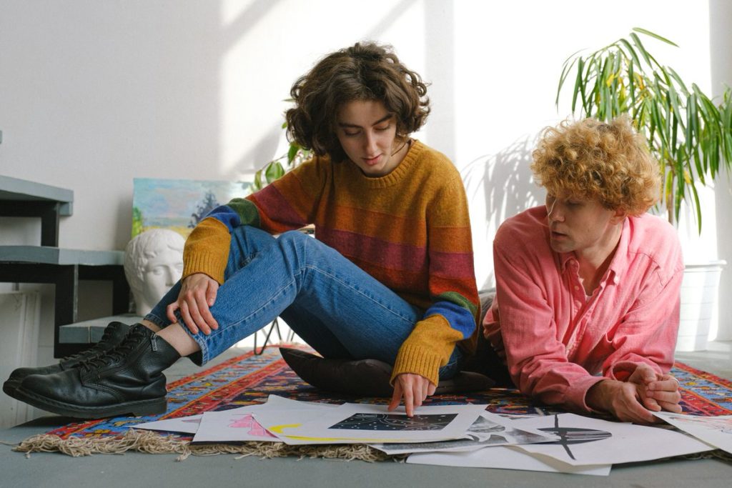 Two people sitting on the ground looking at art pieces