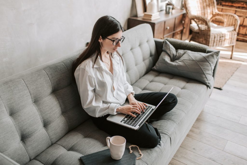 Girl working on a laptop while sitting on the couch