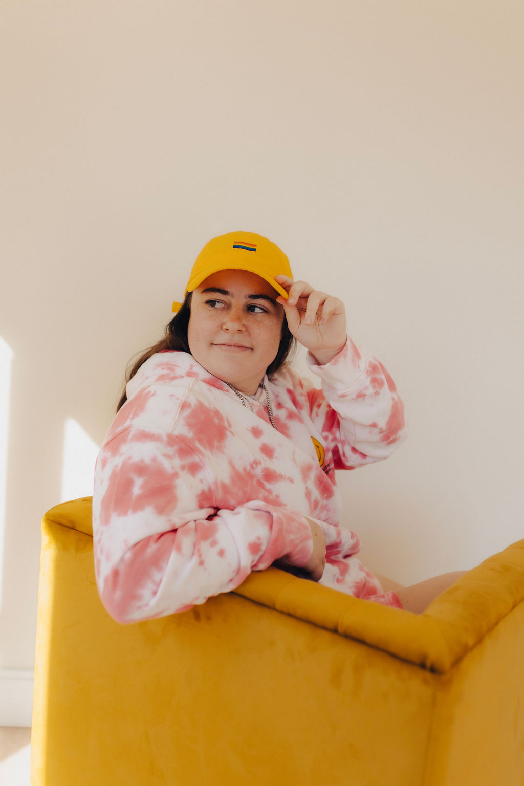 A girl sits in a yellow seat while wearing a yellow Pride hat while thinking about discovery calls.