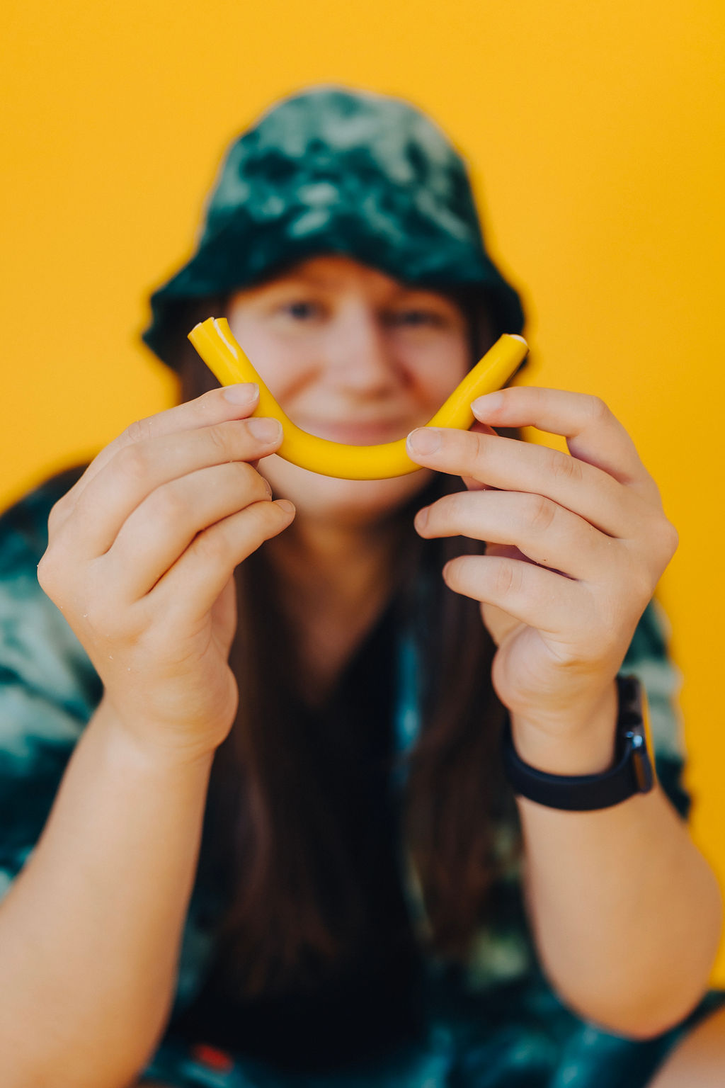 Featured image for questions to ask your web designer. A girl holds a piece of yellow candy in a curved shape