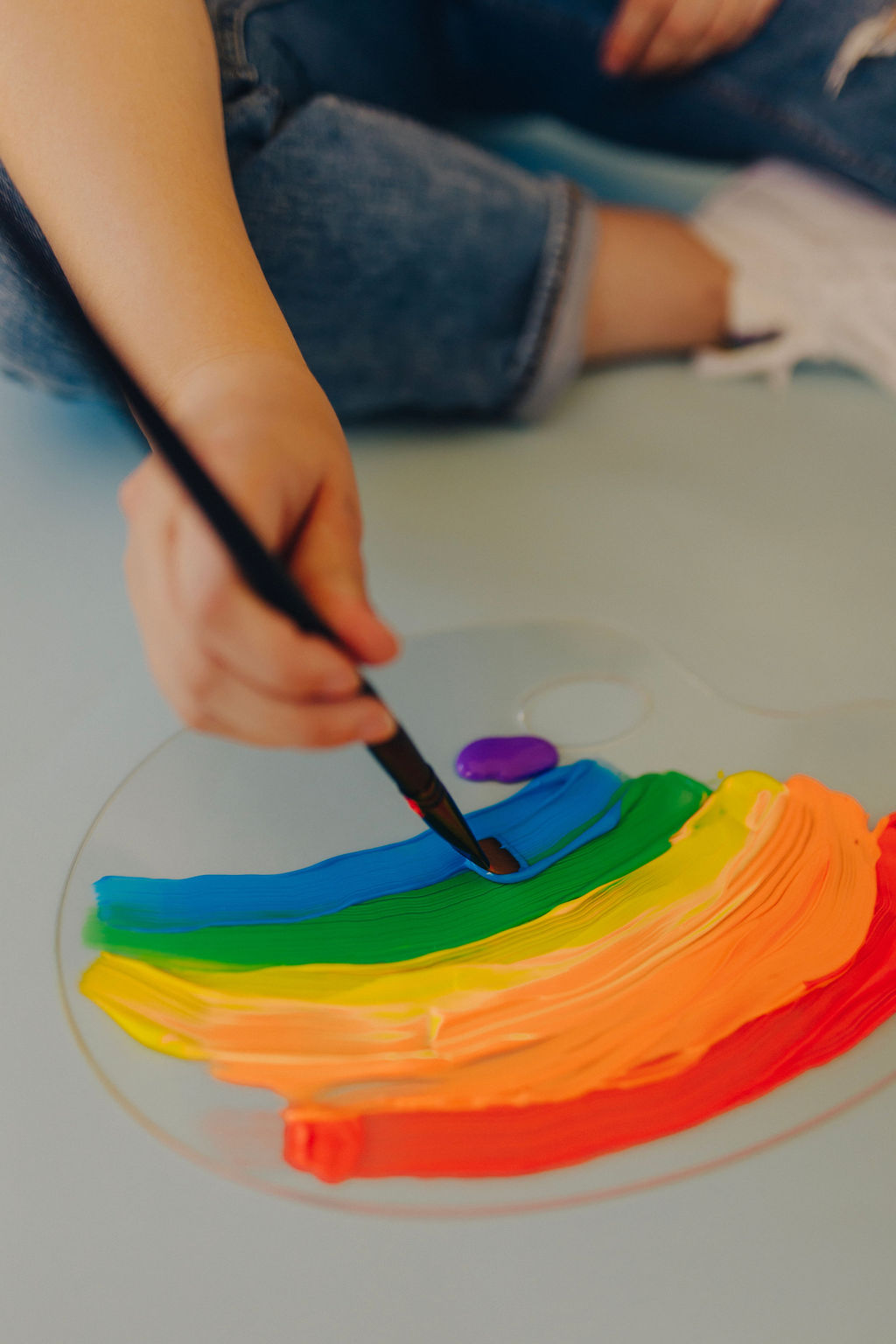 Featured image for how to choose a web designer. A girl is painting rainbow colors on a palette.