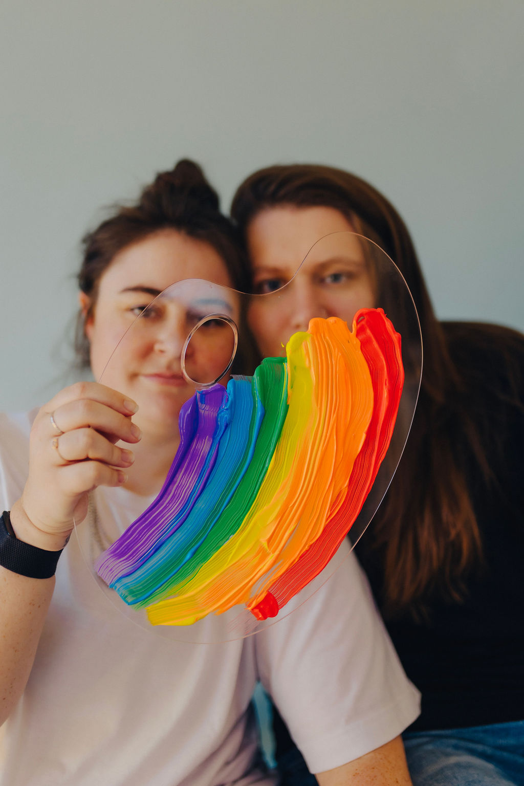featured image for client red flags showing two women sitting next to each other while one holds out a clear paint palette with a rainbow painted on it