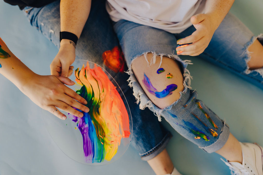 two people sitting on the floor together while finger painting on each other 