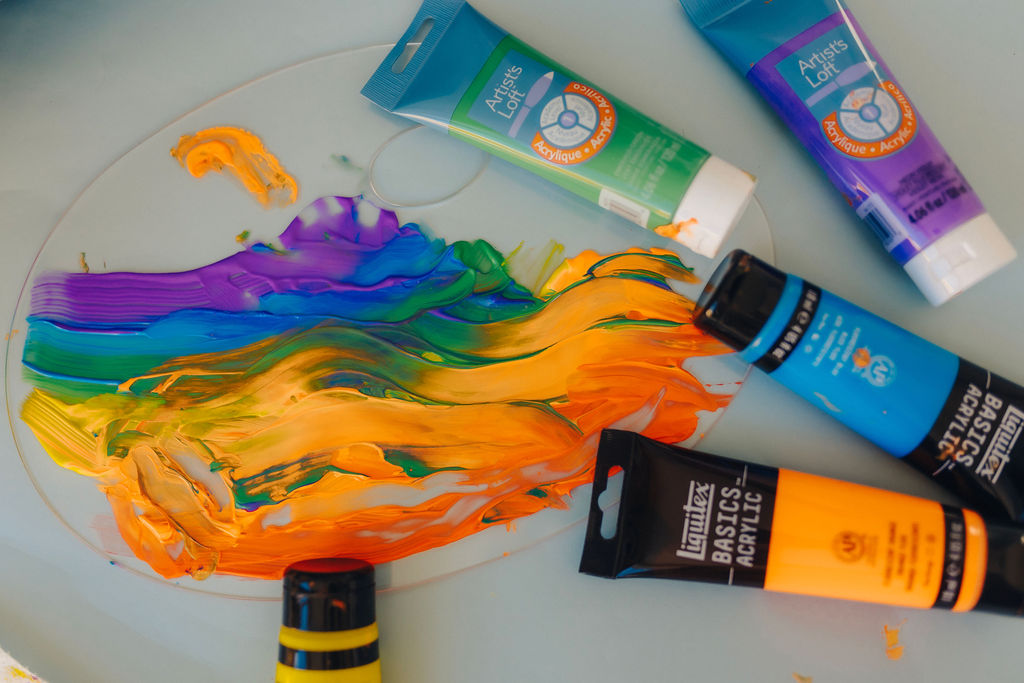 paint smeared across a clear palette with bottle of paint laid next to it 