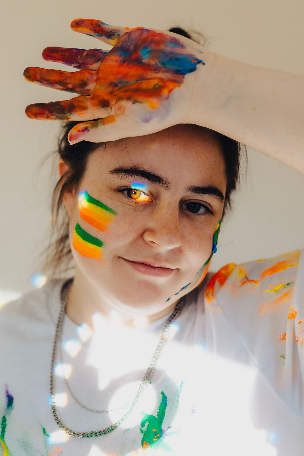 A girl with paint on her face and hands poses while thinking about inspiring photography websites.