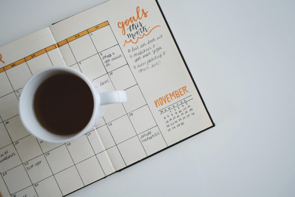 A calendar is open showing the month of November. A mug of coffee sits on the calendar.