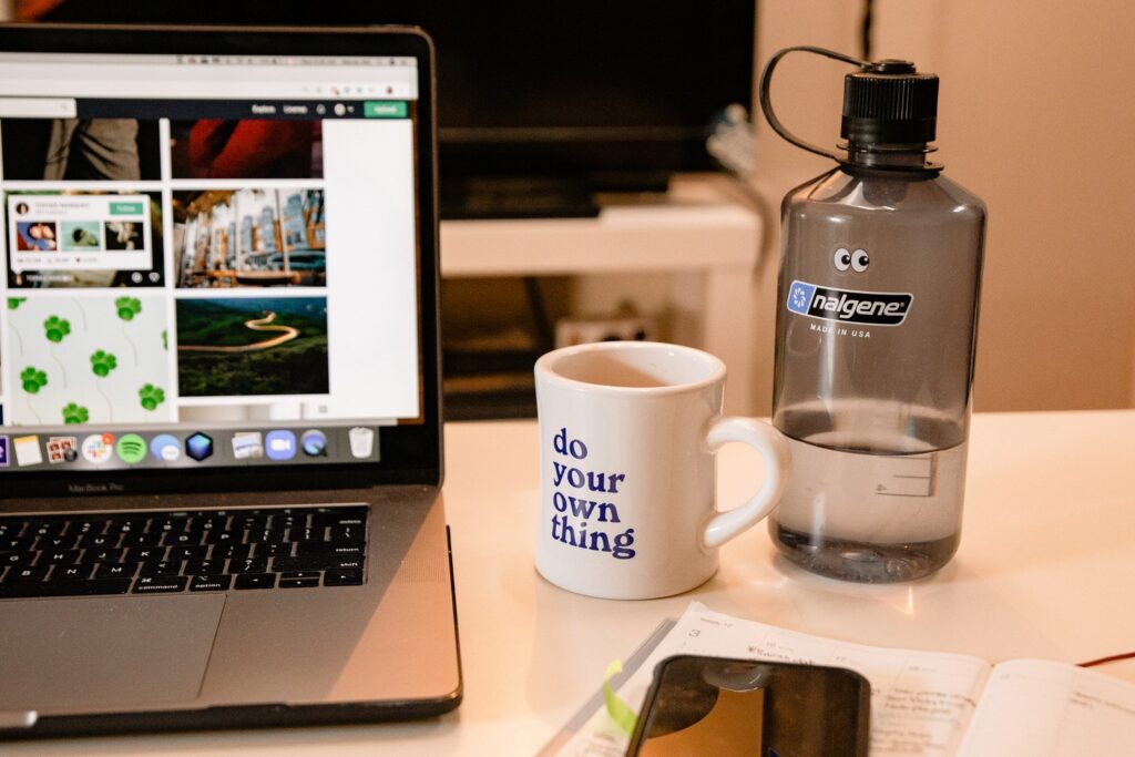 a mug and water bottle sitting next to an open laptop 