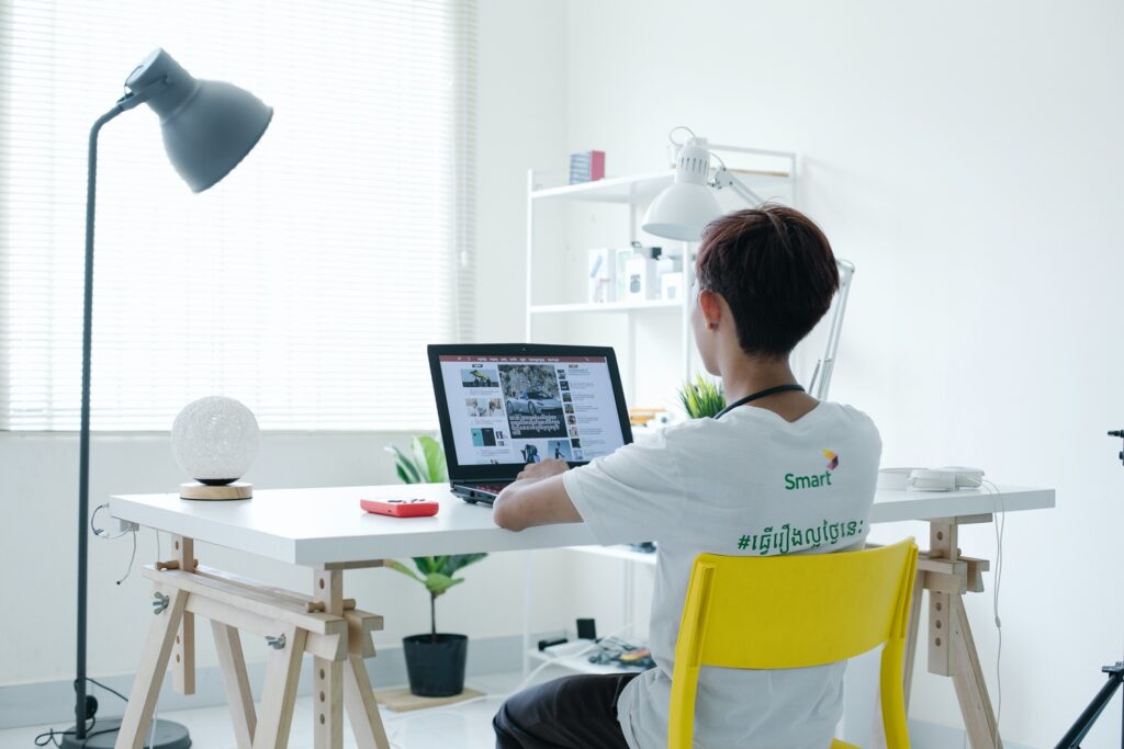 A person sits at their desk working on a computer in a white room.