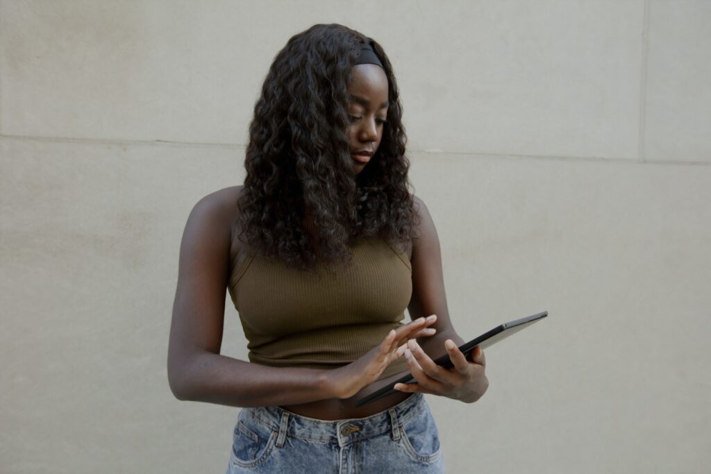 A woman stands while touching an ipad.