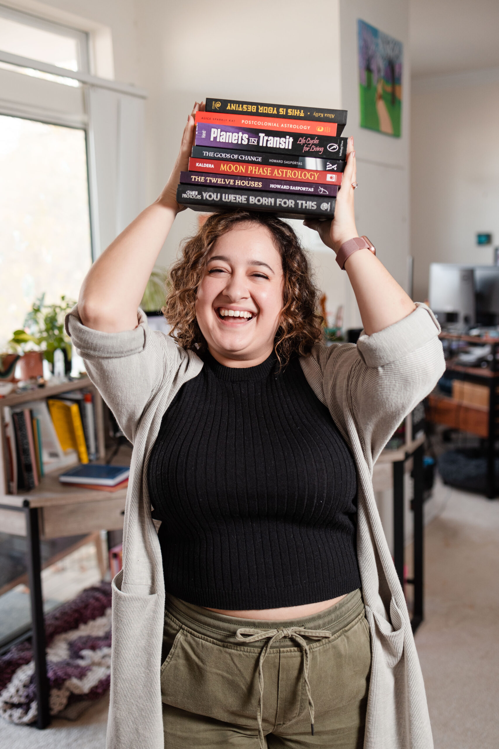 A girl smiles while holding astrology for business books on her head.