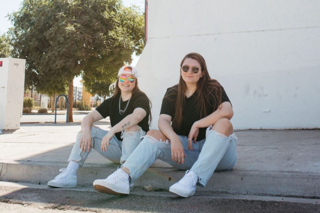 Two girls sitting on a curb outdoors.