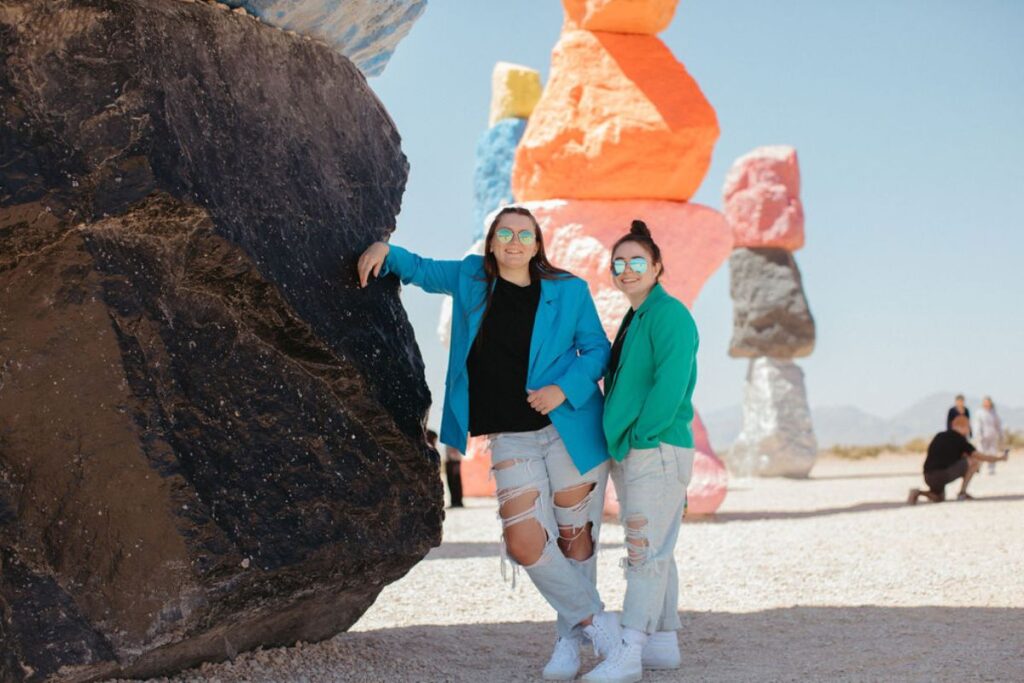 Two girls smiling standing next to colorful rocks.