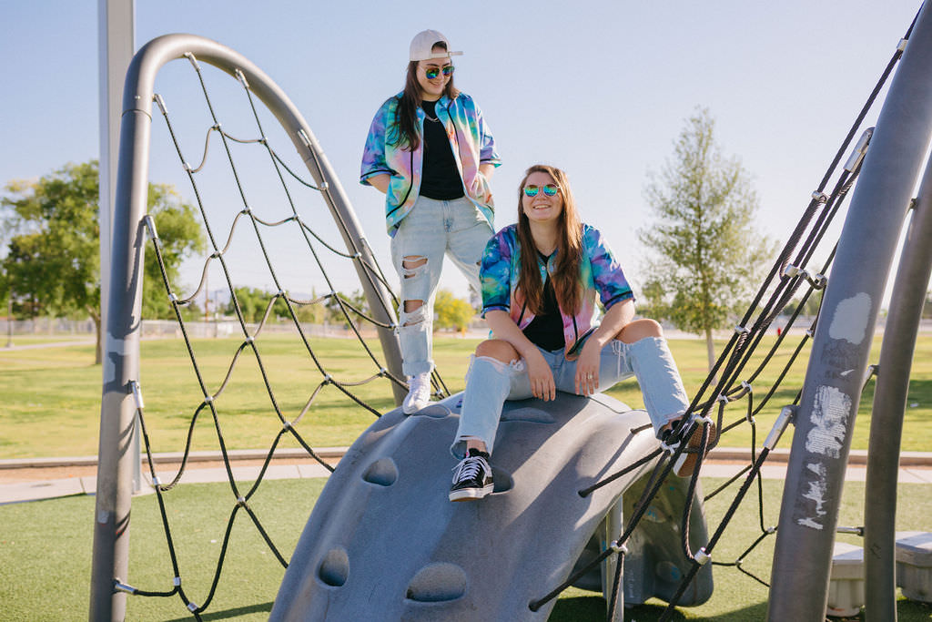 One woman standing on a piece of playground equipment while another sits next to her. 