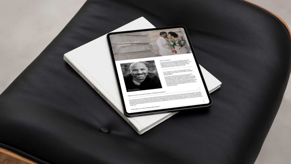 An elegant presentation of a professional photography website on a tablet, lying on a black leather chair next to a white hardcover book, indicating a sleek, modern design aesthetic.