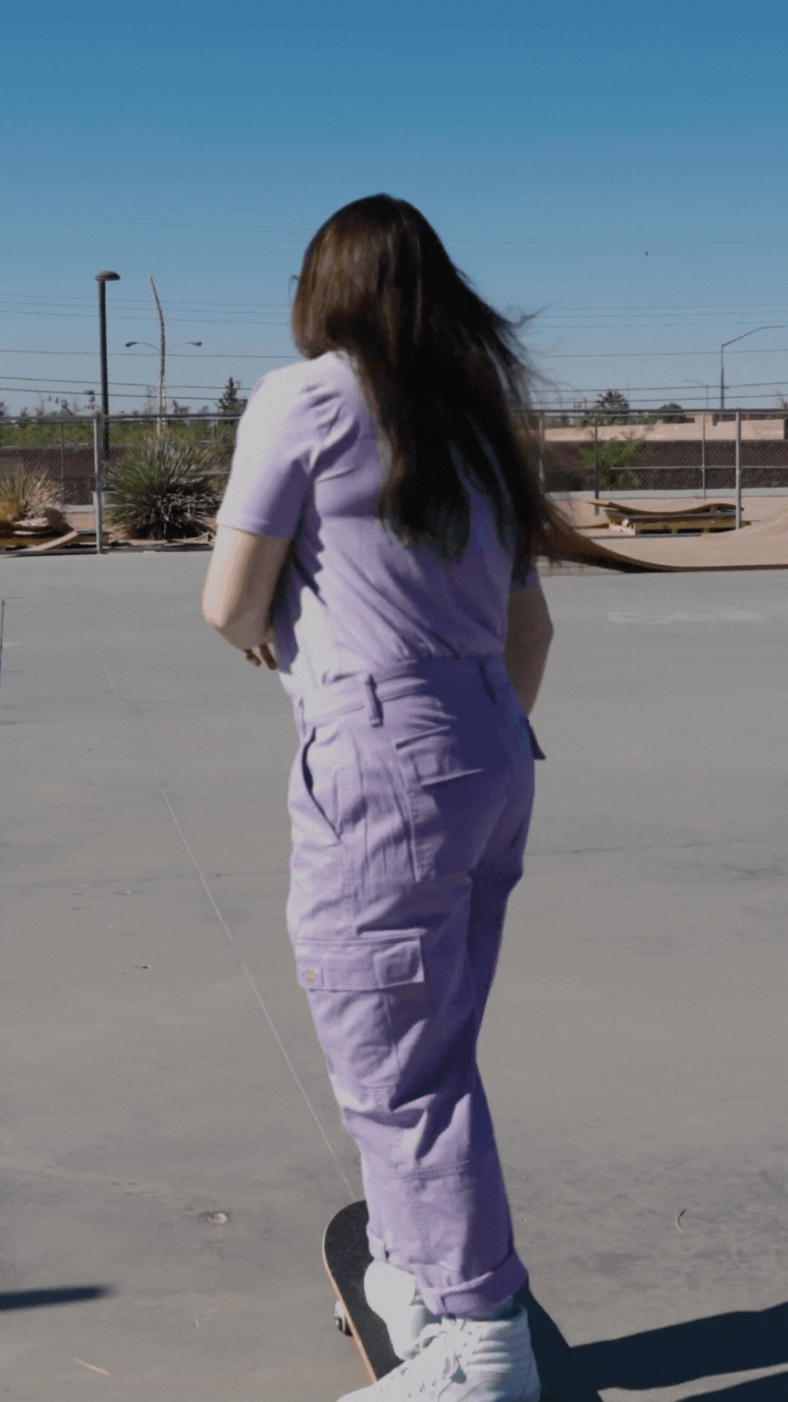 Girl in a purple outfit skateboarding away.