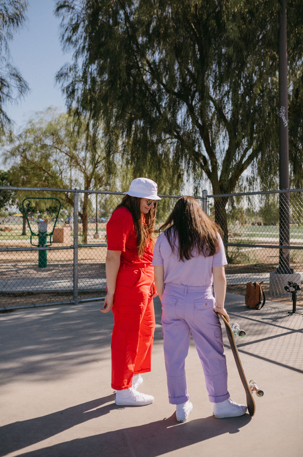 Two women in colorful attire discussing over a skateboard in an outdoor setting, representing collaboration in the brand design process