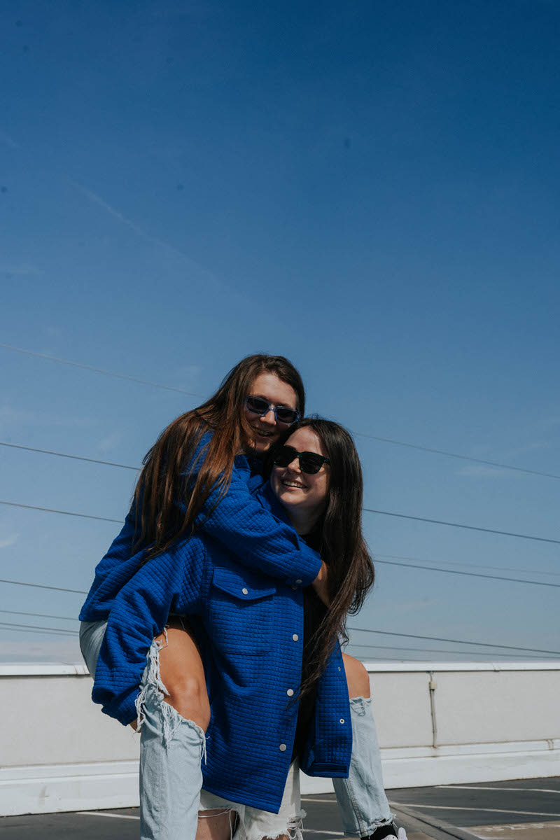 A woman holding another woman on her back as they both smile