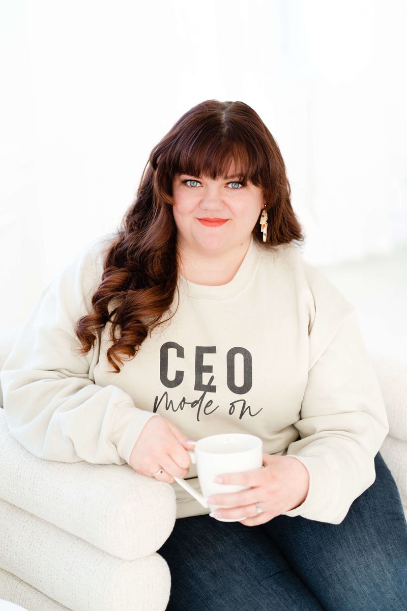 A woman sitting on a couch holding a coffee cup and smiling