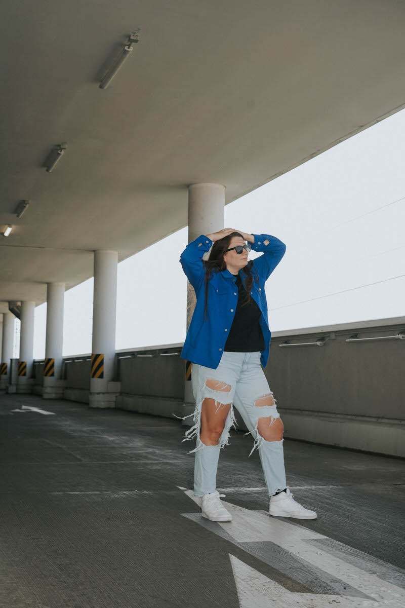 A woman standing in a parking garage with her hands on her head.