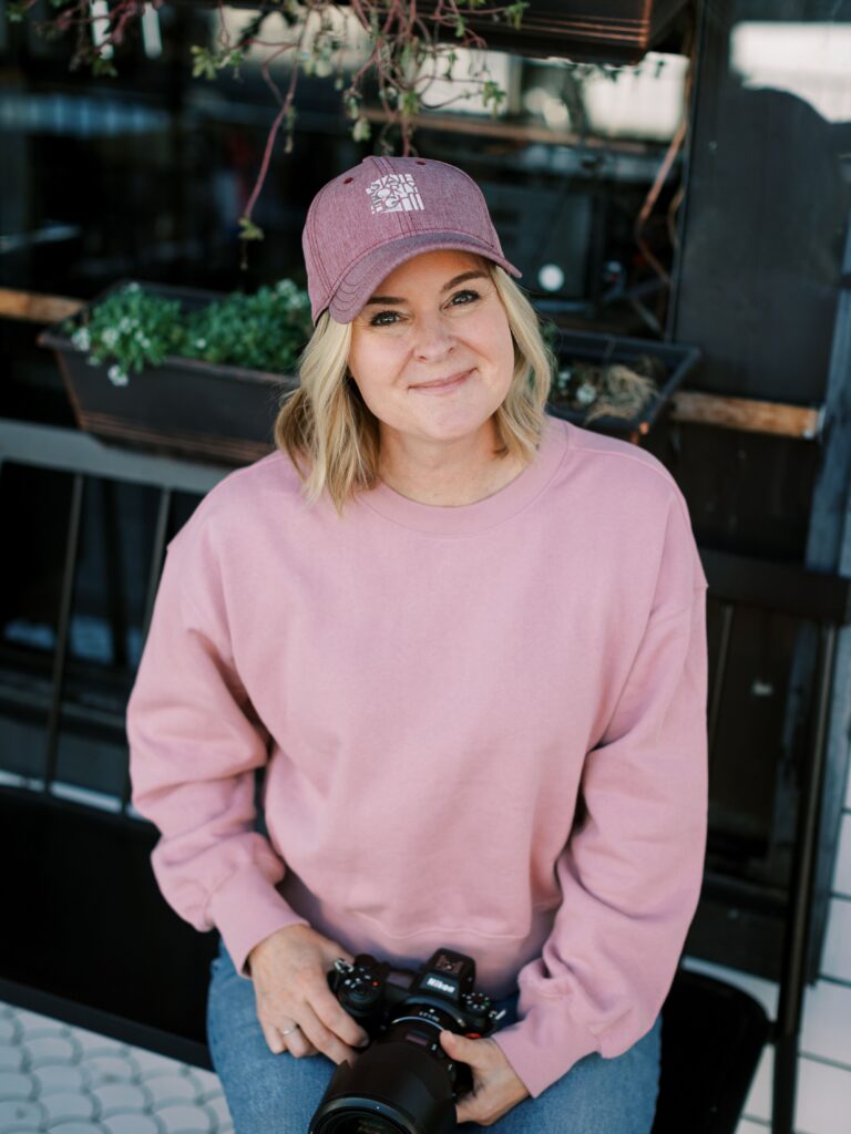 A person sitting down and smiling with a camera in their lap