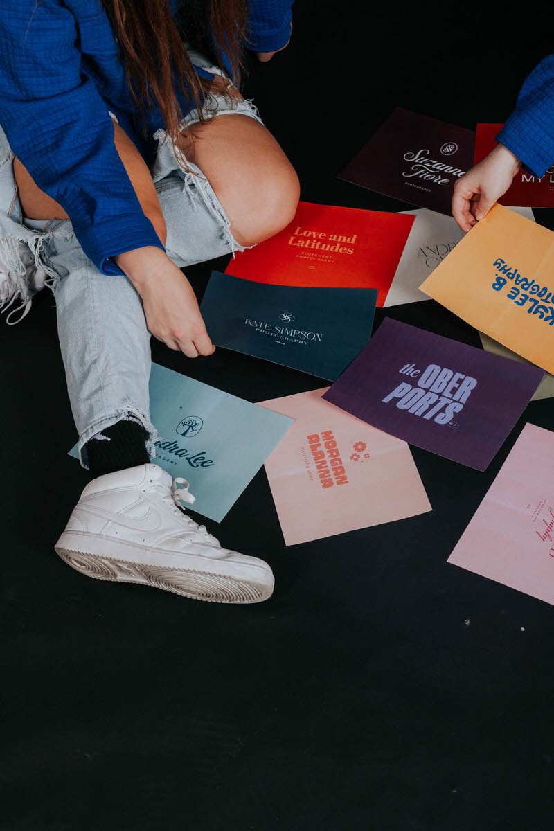 Two people sitting on the floor with colorful printouts around them.