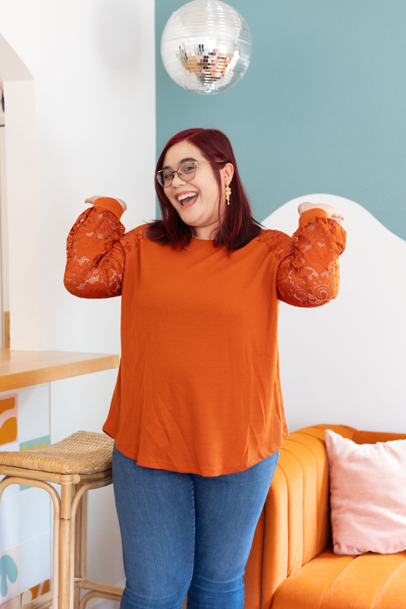 A woman smiling with her hands up by her shoulders