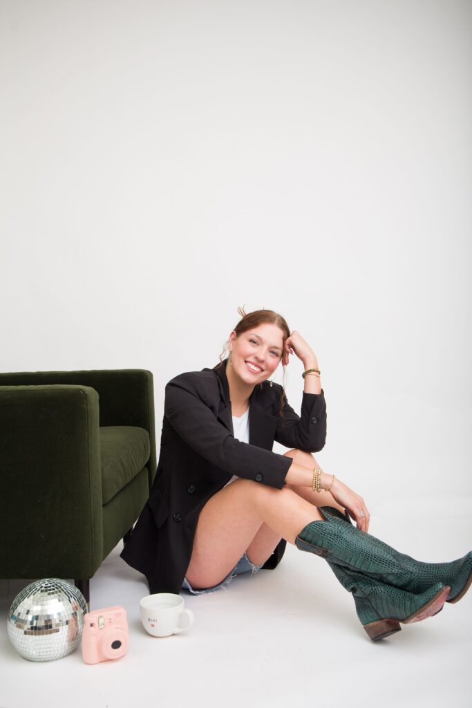 A woman sitting on the ground smiling with her hands on her knees. 