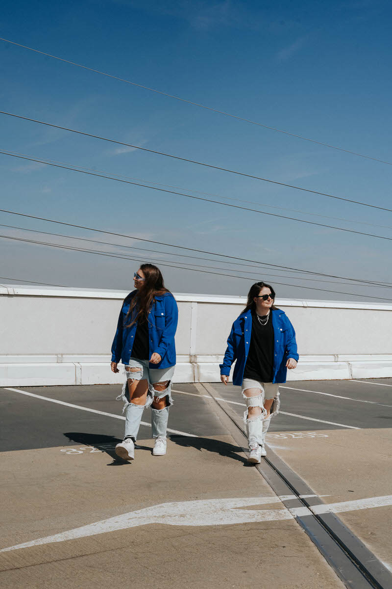 Two women walking on the top floor of a parking garage, looking in opposite directions.