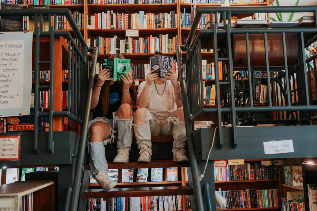 KP and Jessie read books covering their faces on stairs.