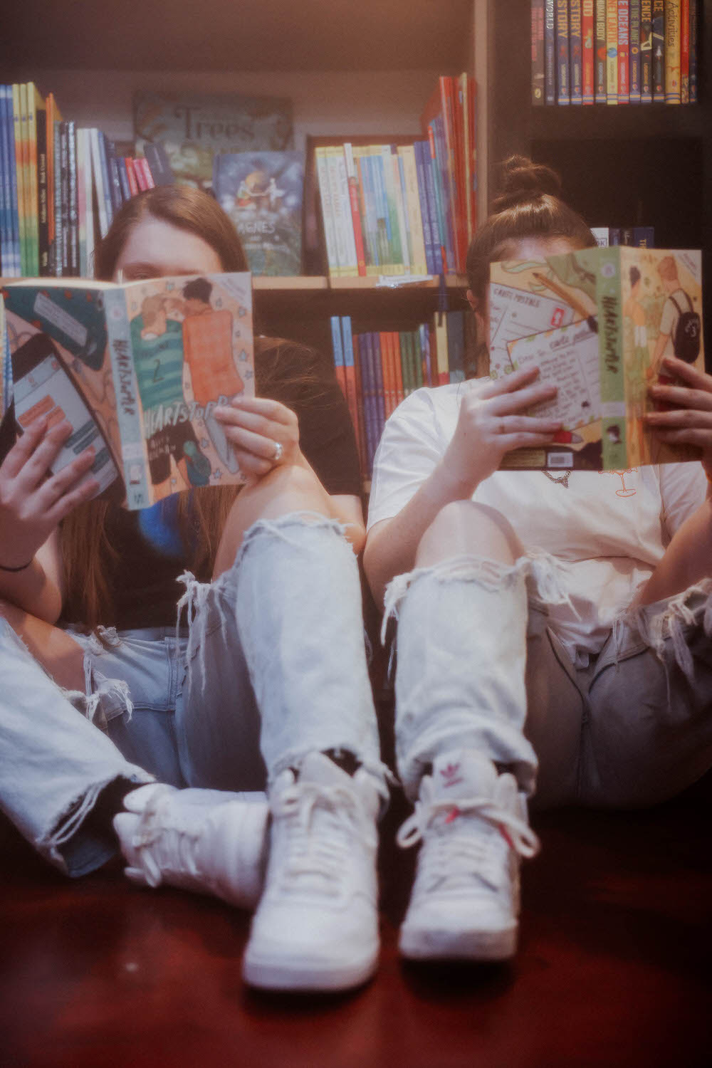 KP and Jessie sit on the floor reading a book.