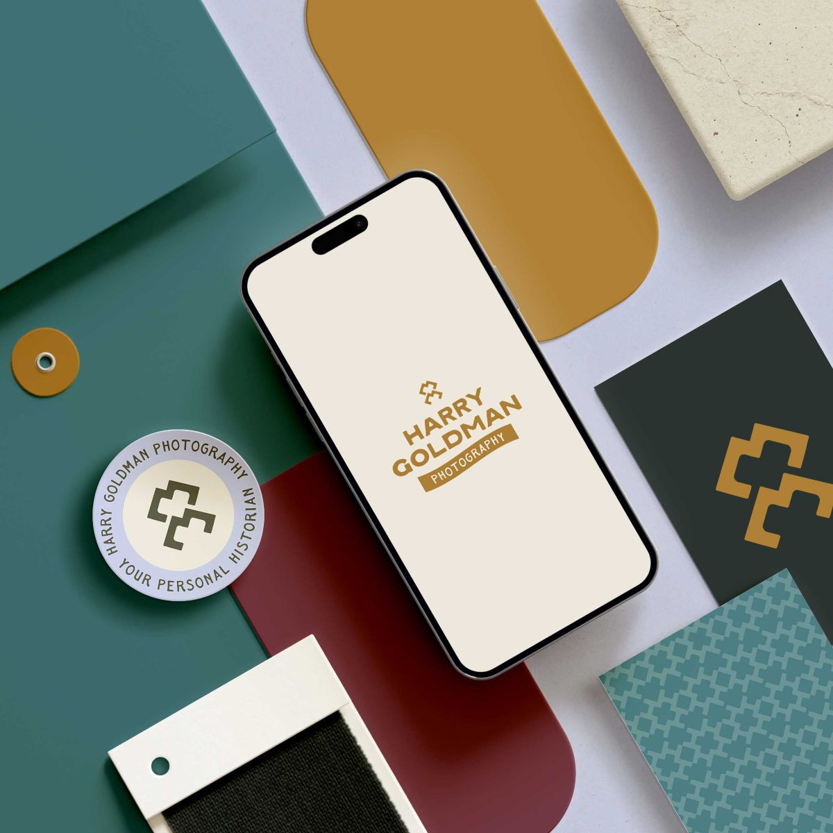 a mobile phone displaying harry goldman photography's website along with other branding elements for their business