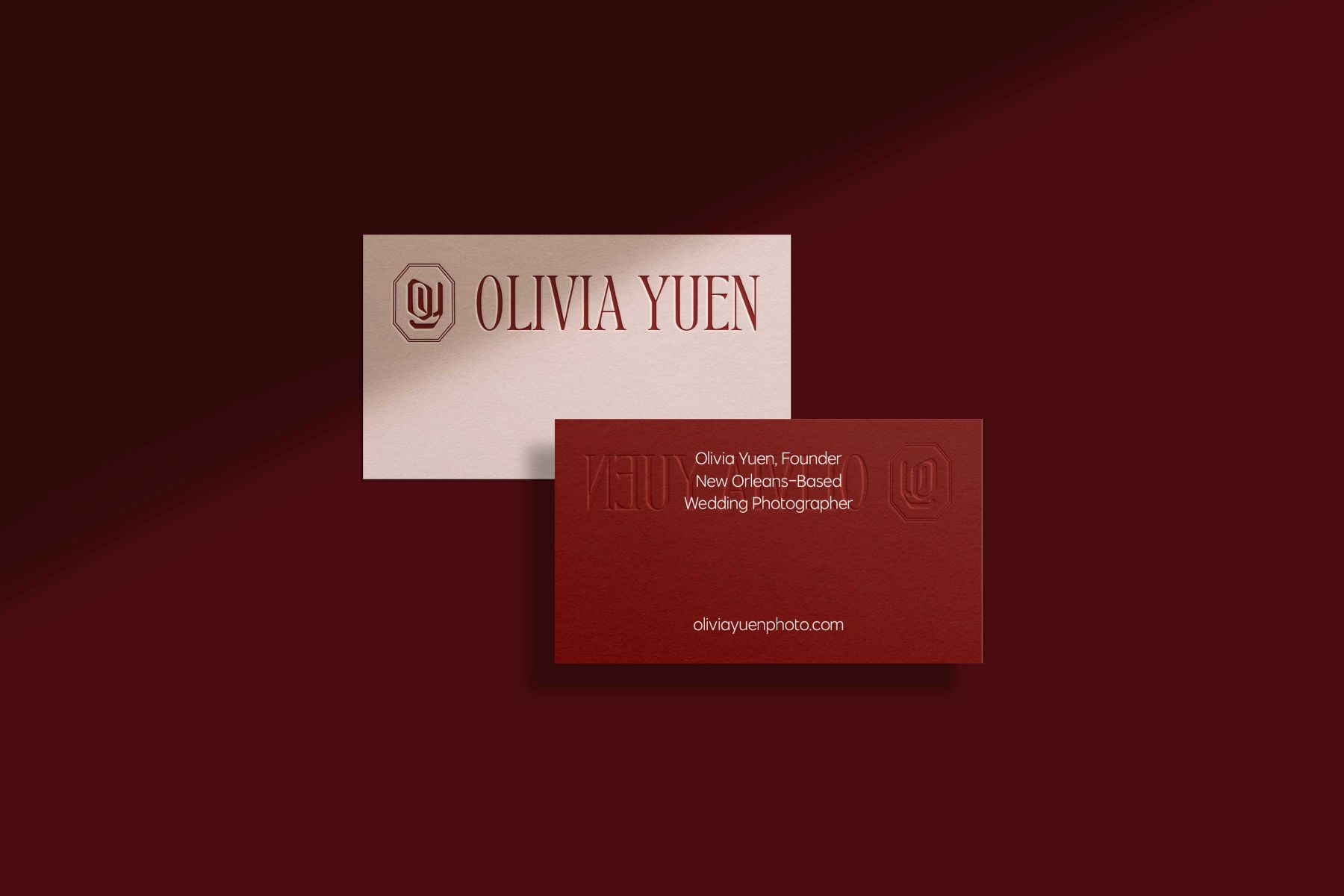 one white and red business card for Olivia Yuen photography set against a maroon backdrop