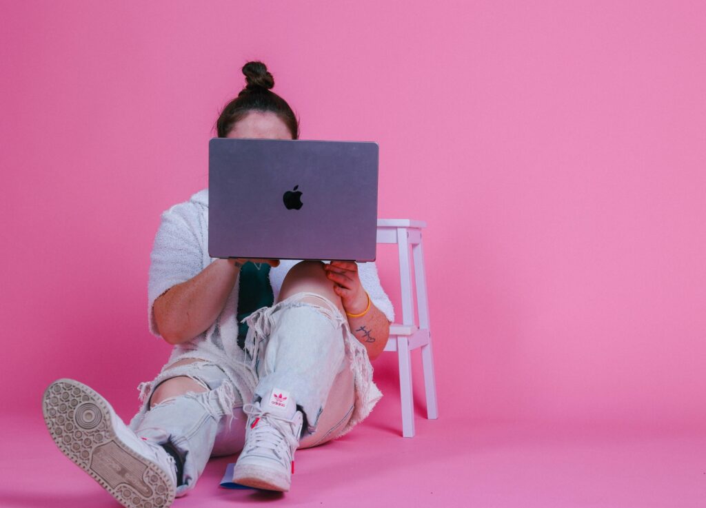 A person holds up their laptop on their knee.