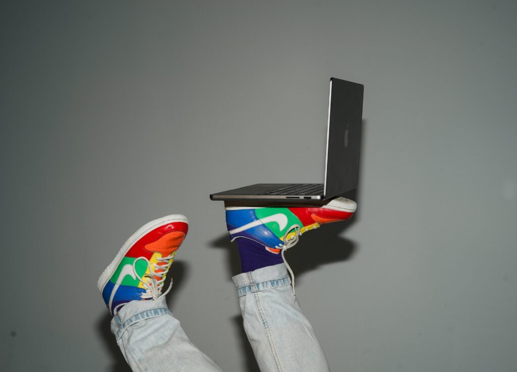 A laptop is held up by rainbow sneakers.
