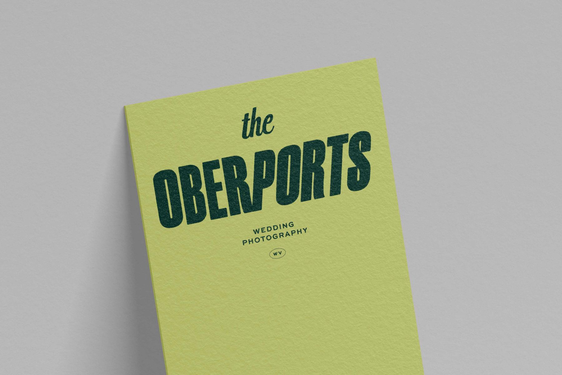 logo for the oberports wedding photography on a green piece of paper set against a gray backdrop