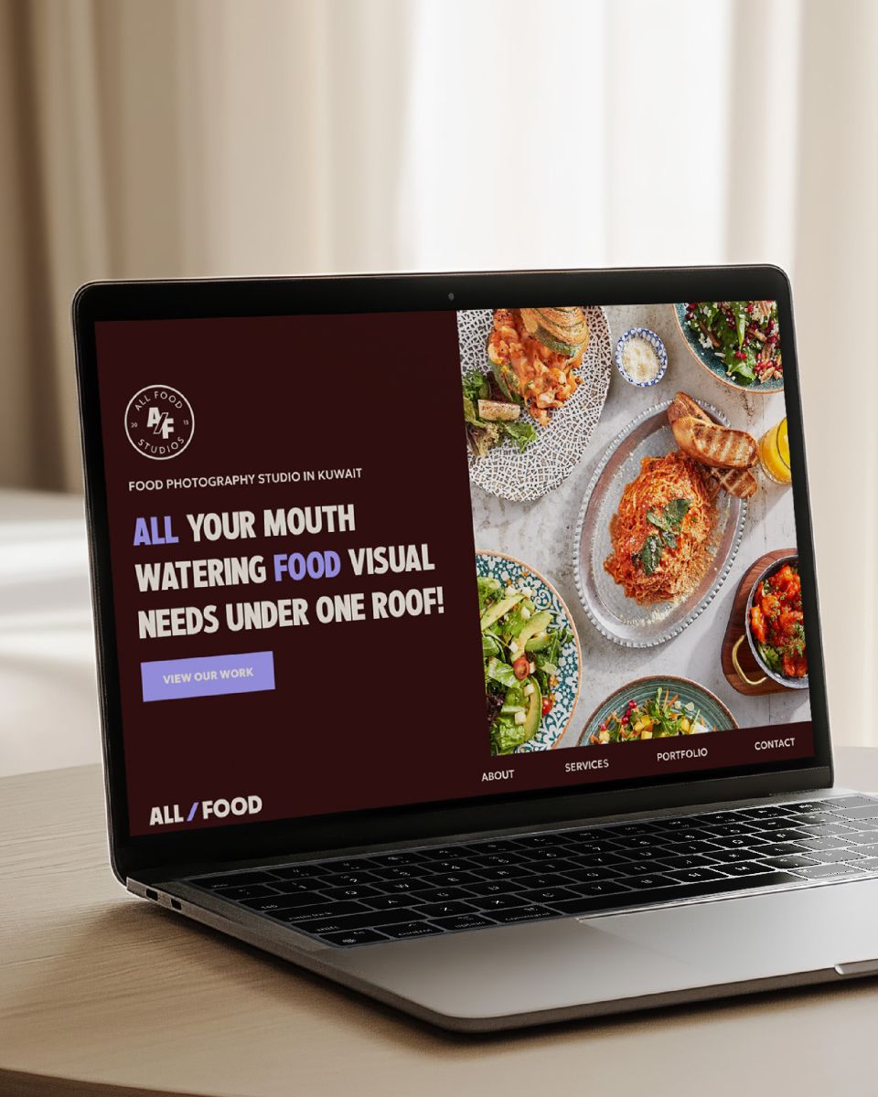 a laptop on top of a table displaying a website page for all food studios 