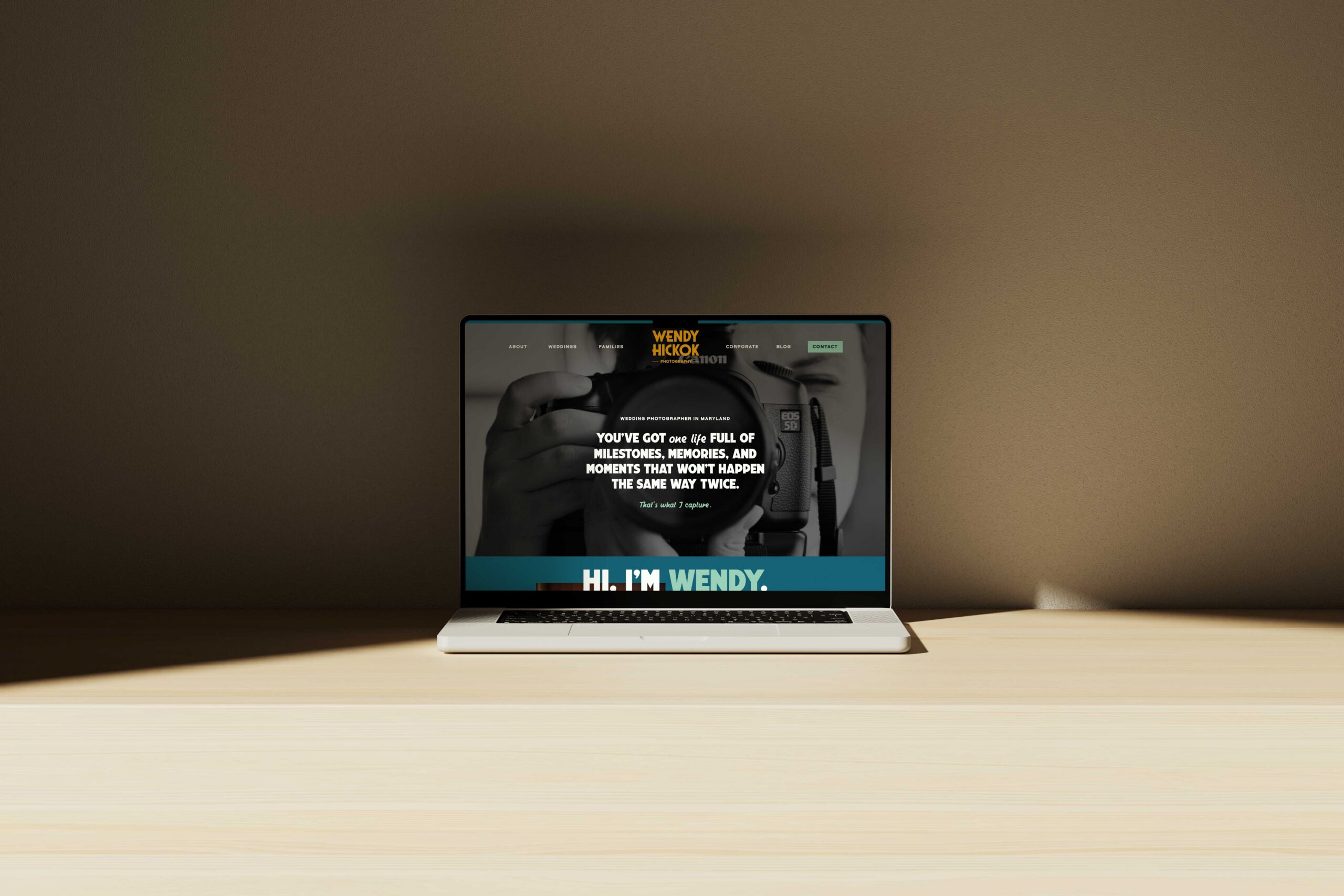 a photographer's website pulled up on a laptop sitting on top of table 