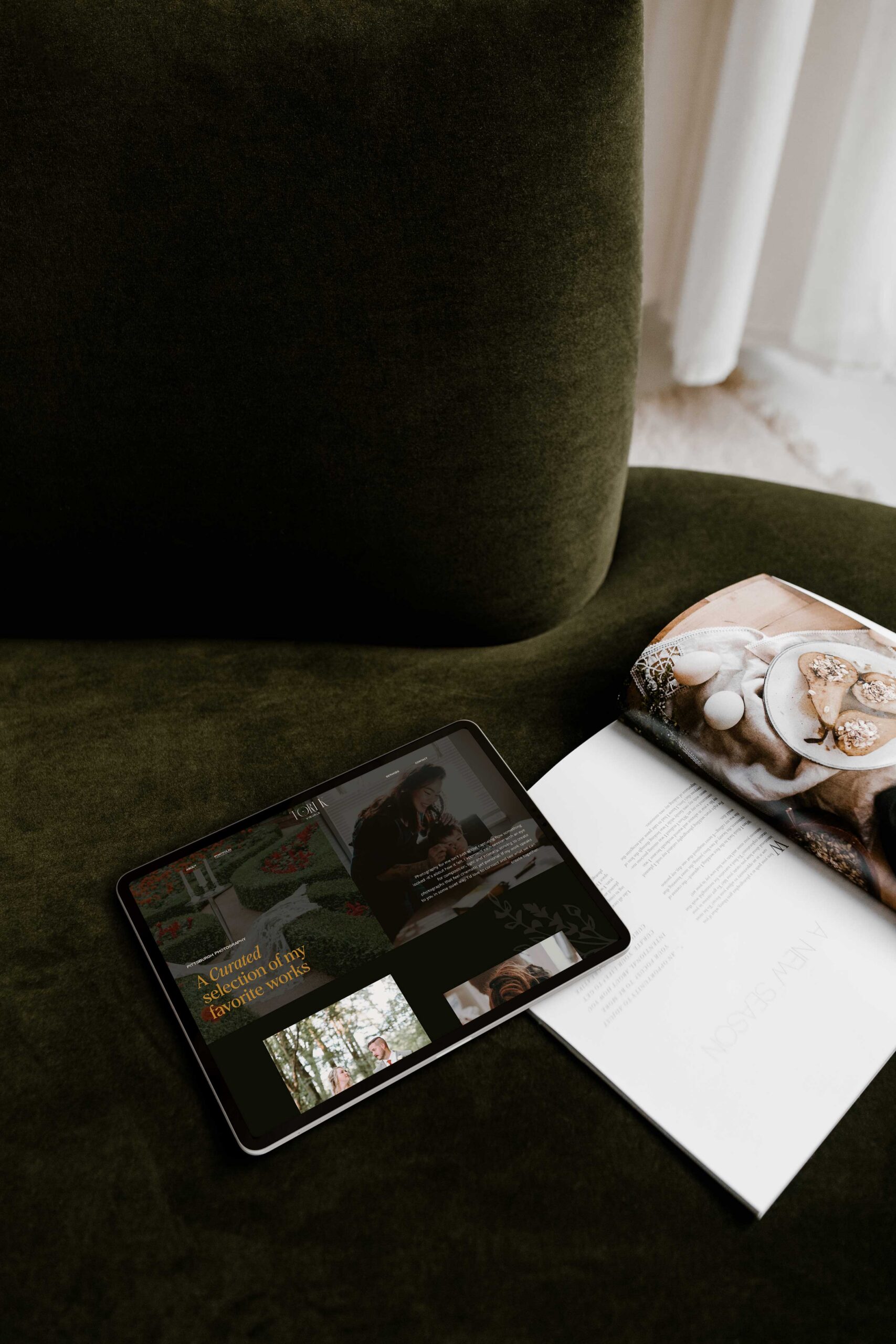 a tablet on top of a green couch next to a magazine the tablet is displaying the website for tori k visuals