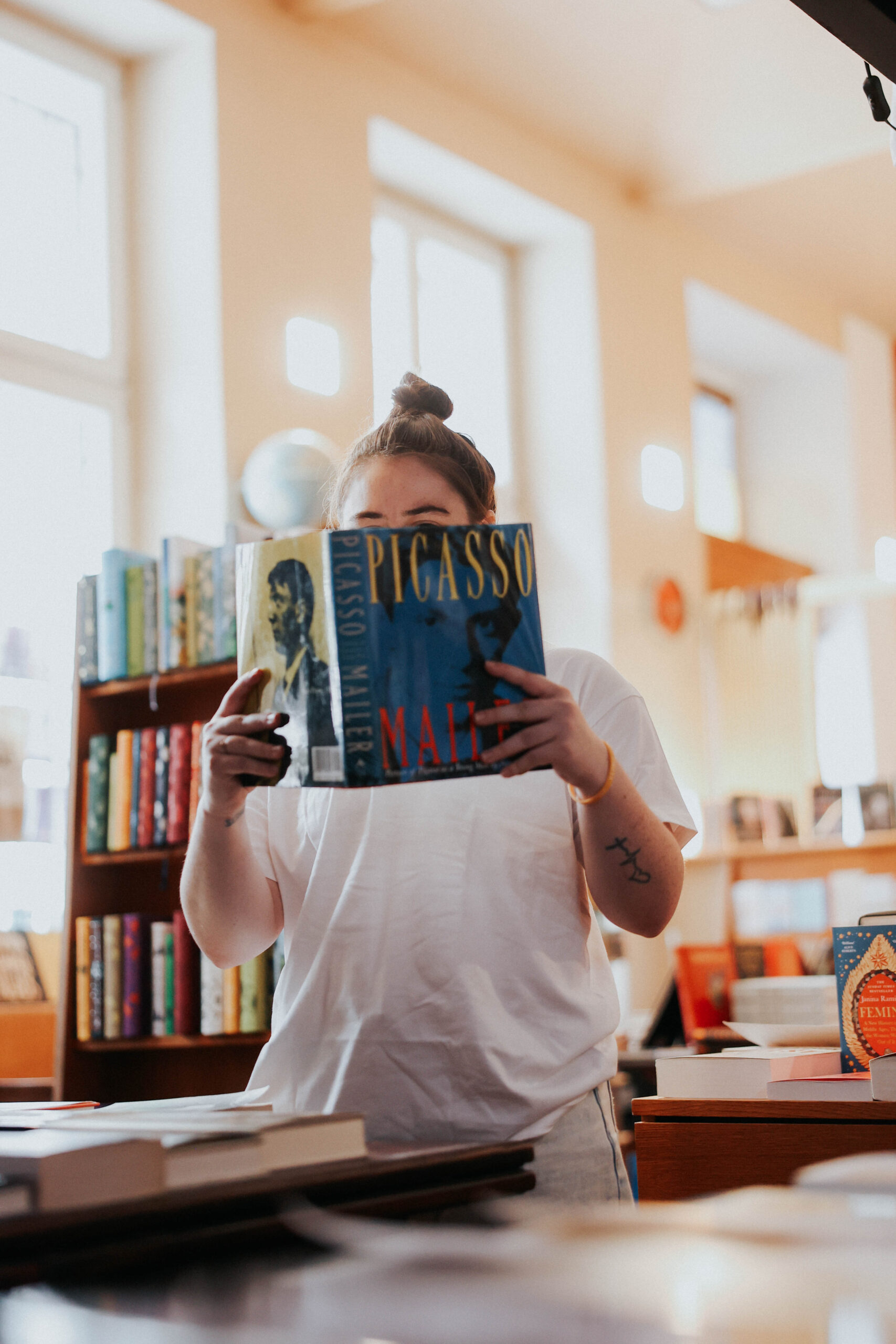 a person in a bookstore holding up a book and reading int 
