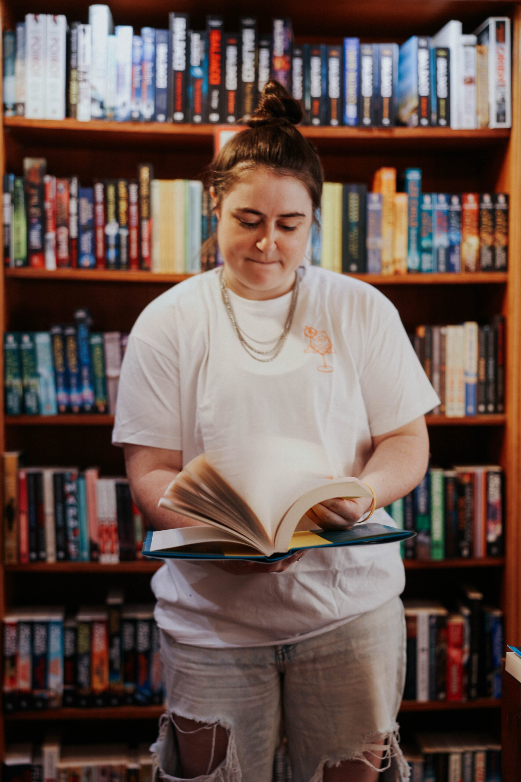 a person in front of a bookshelf in a bookstore flipping through pages in a book 