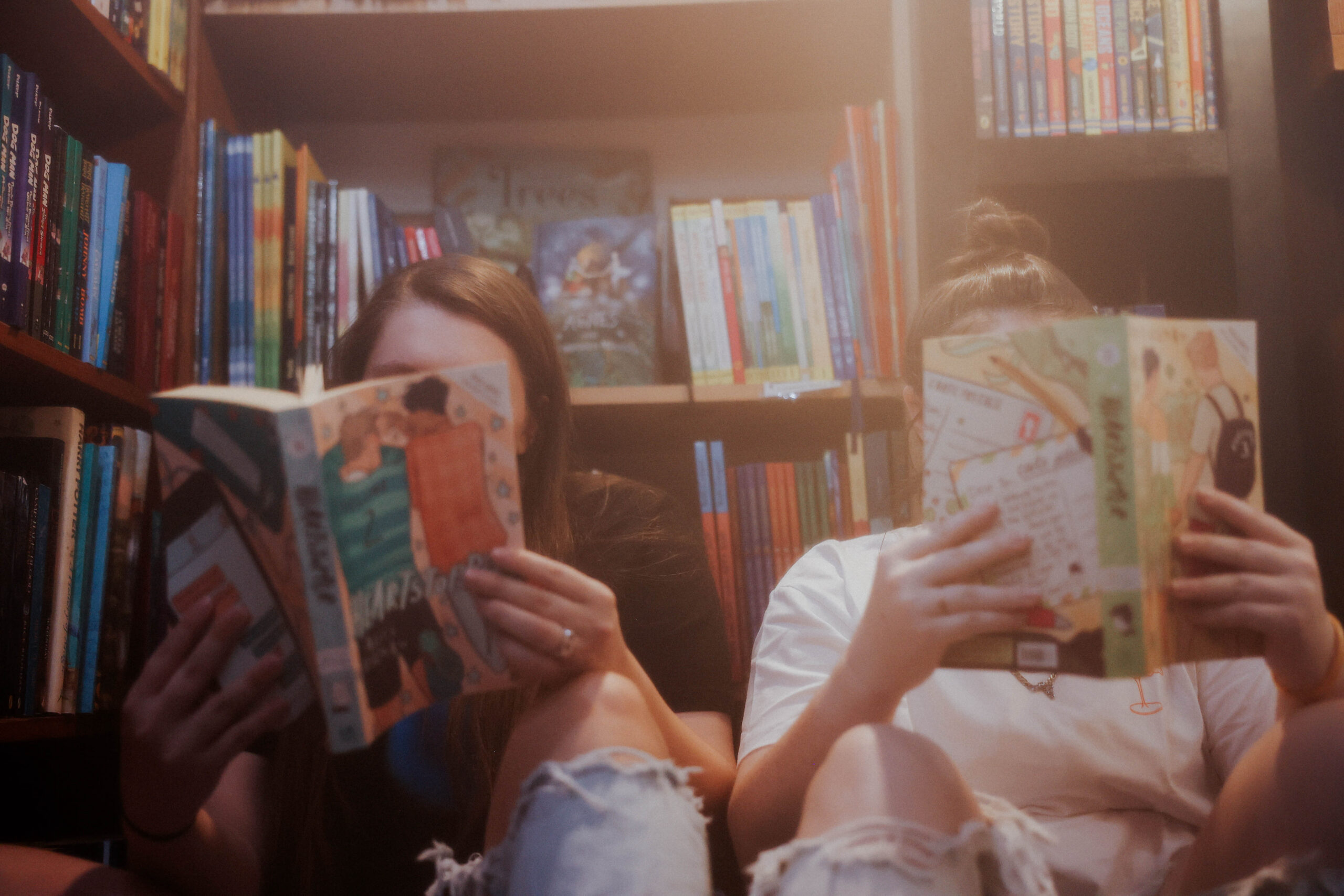 two people sitting on the floor in a bookstore reading books side by side